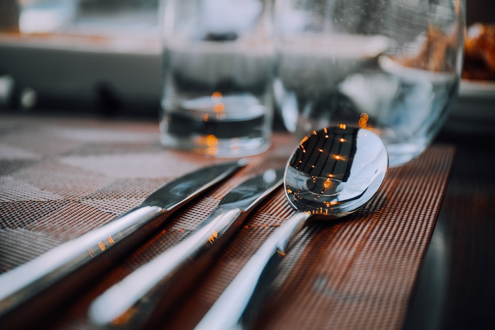 spoon and knives on table top by glasses