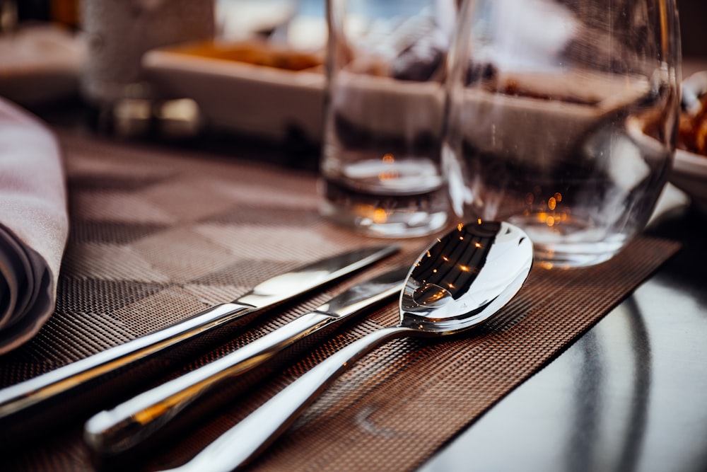 silver spoon and table knives on brown board