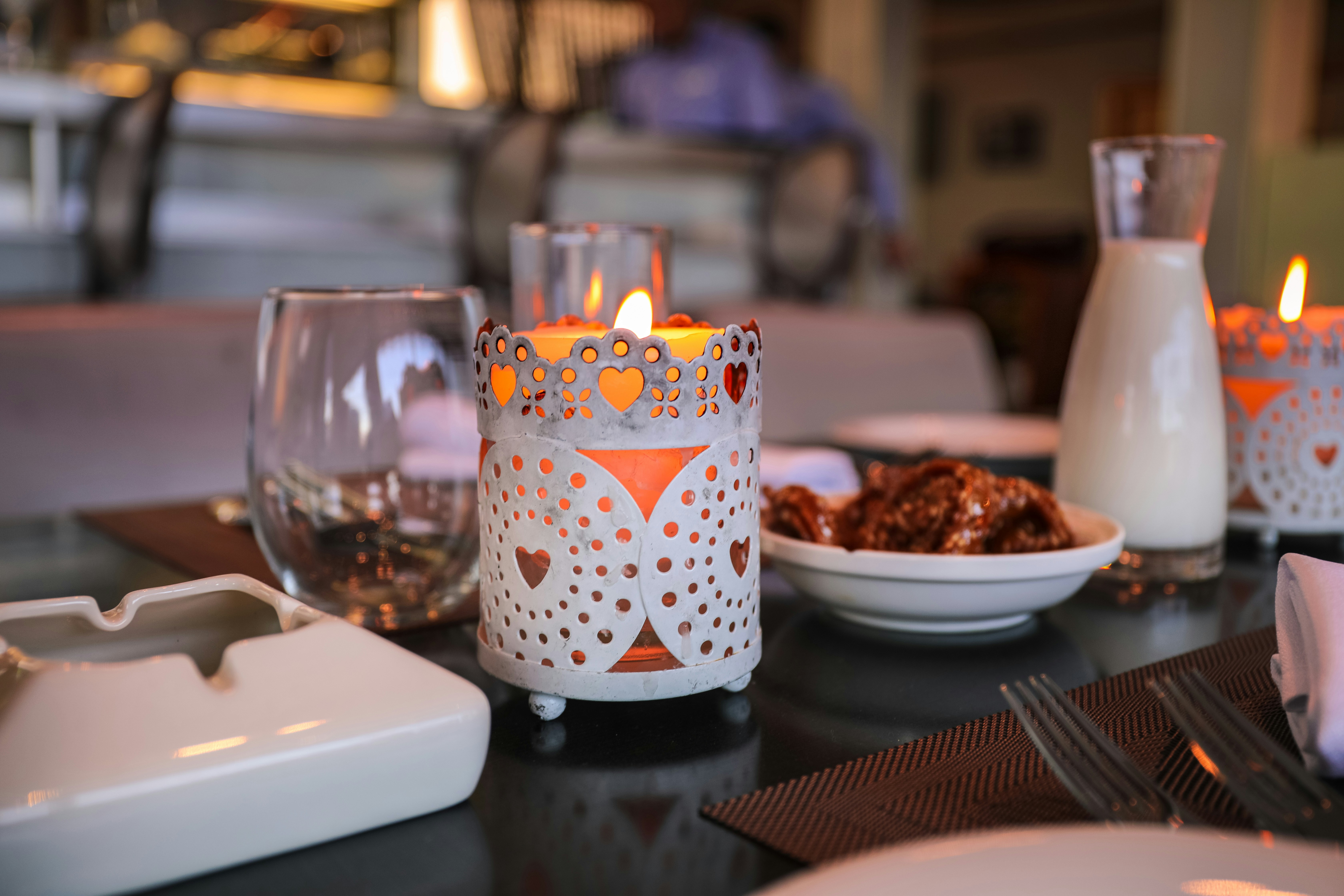 Candle holder, wine glass and dishes on a table