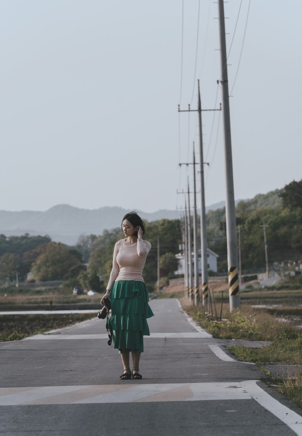 woman walking and fixing her hair while holding DSLR camera