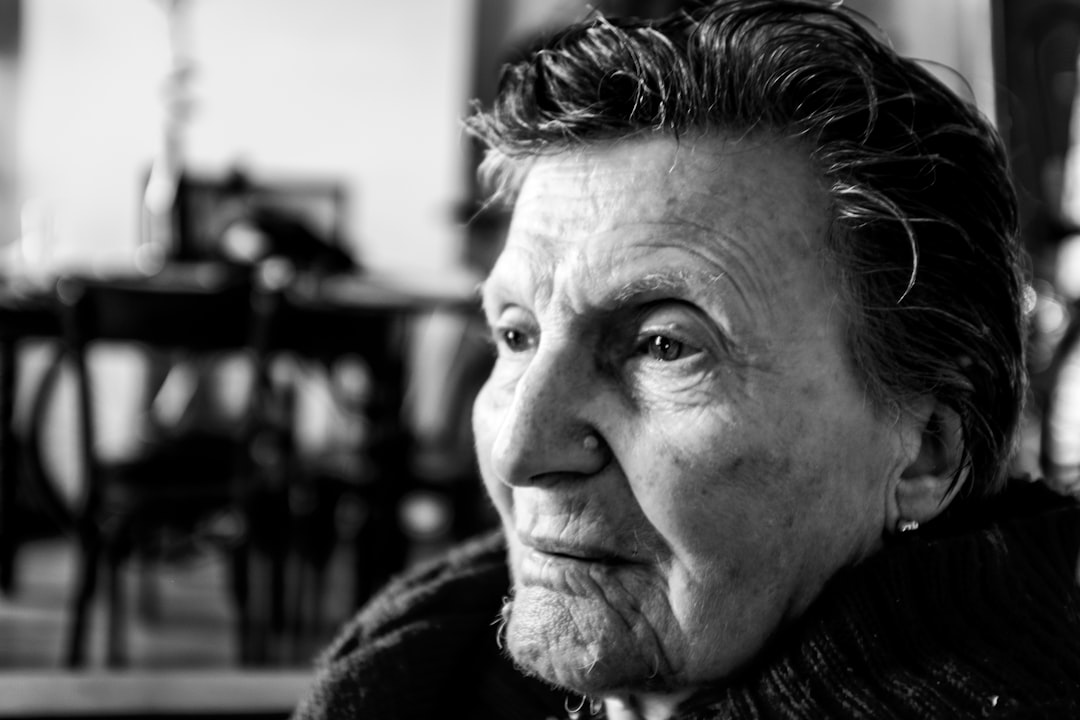 grayscale photo of man sitting near table