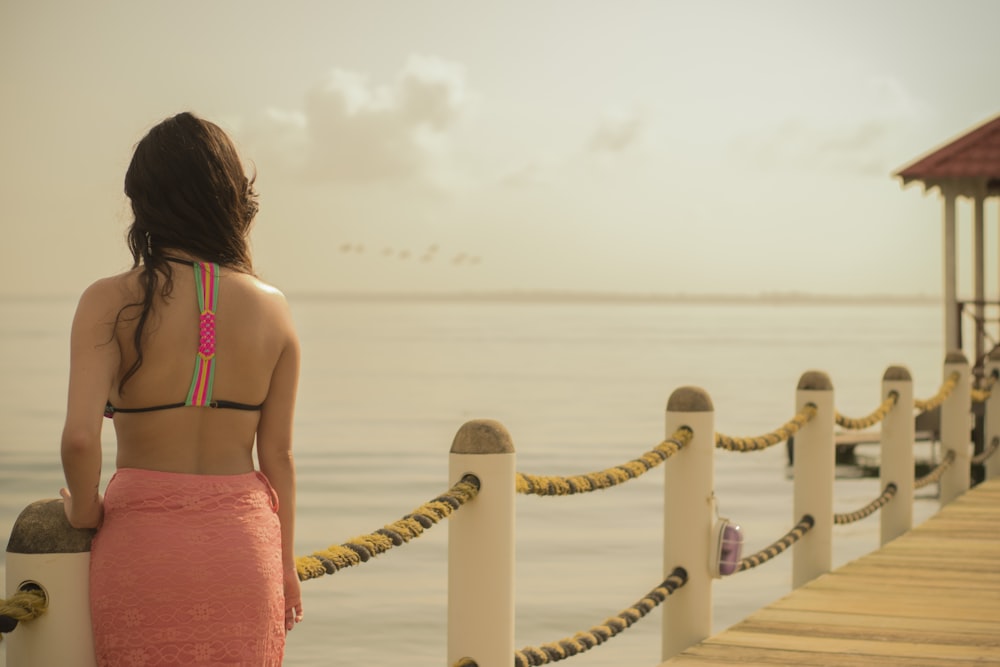 Frau im rosa Rock steht auf der Promenade am Meer