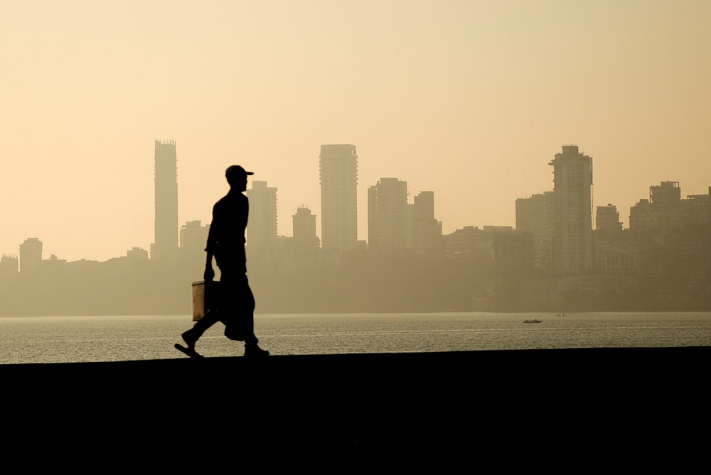 silhouette of man walking near the ocean