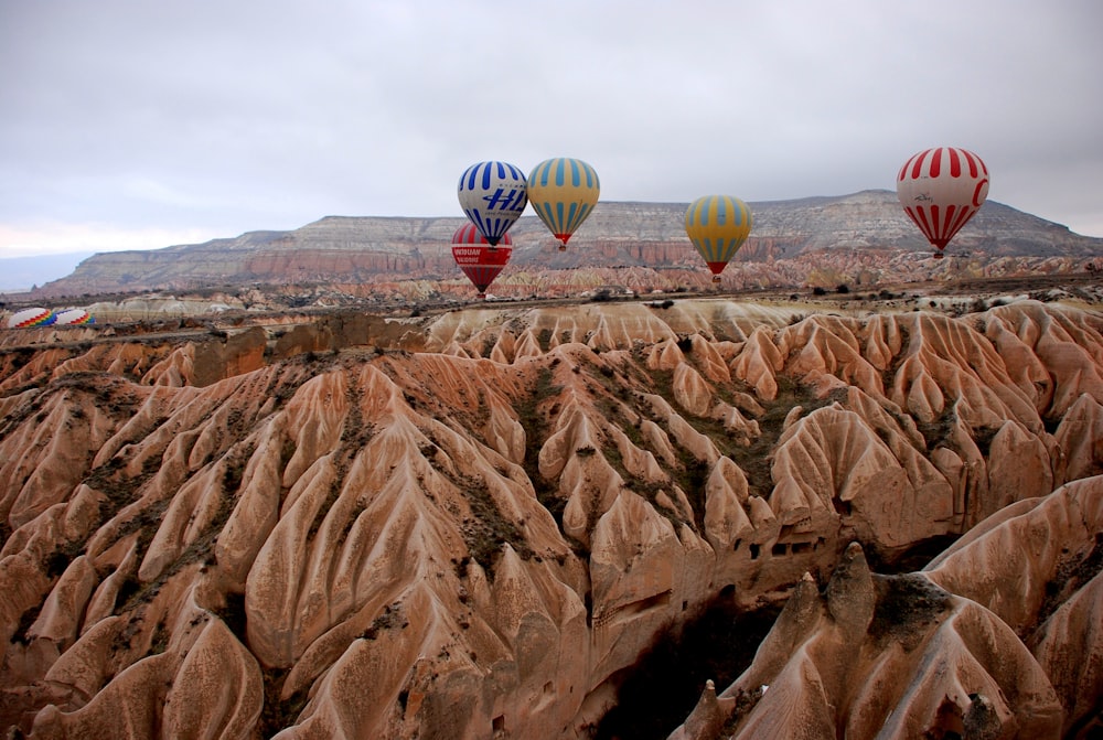 five hot air balloons floating over rock formation