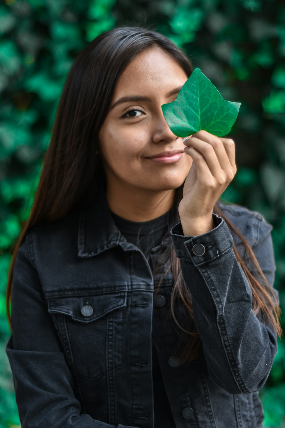 femme souriante tenant une feuille verte