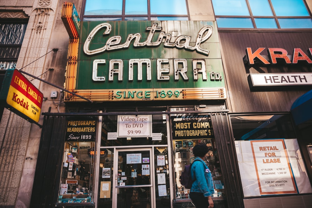 person standing beside Central Camera store-front