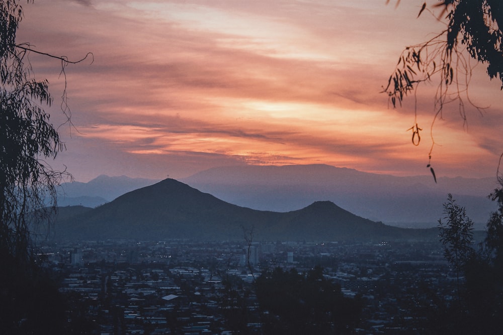 Céu nublado laranja sobre a cidade e montanhas