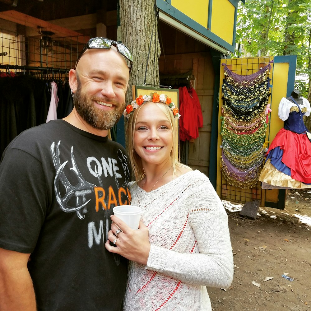 man and woman standing near trees and apparels