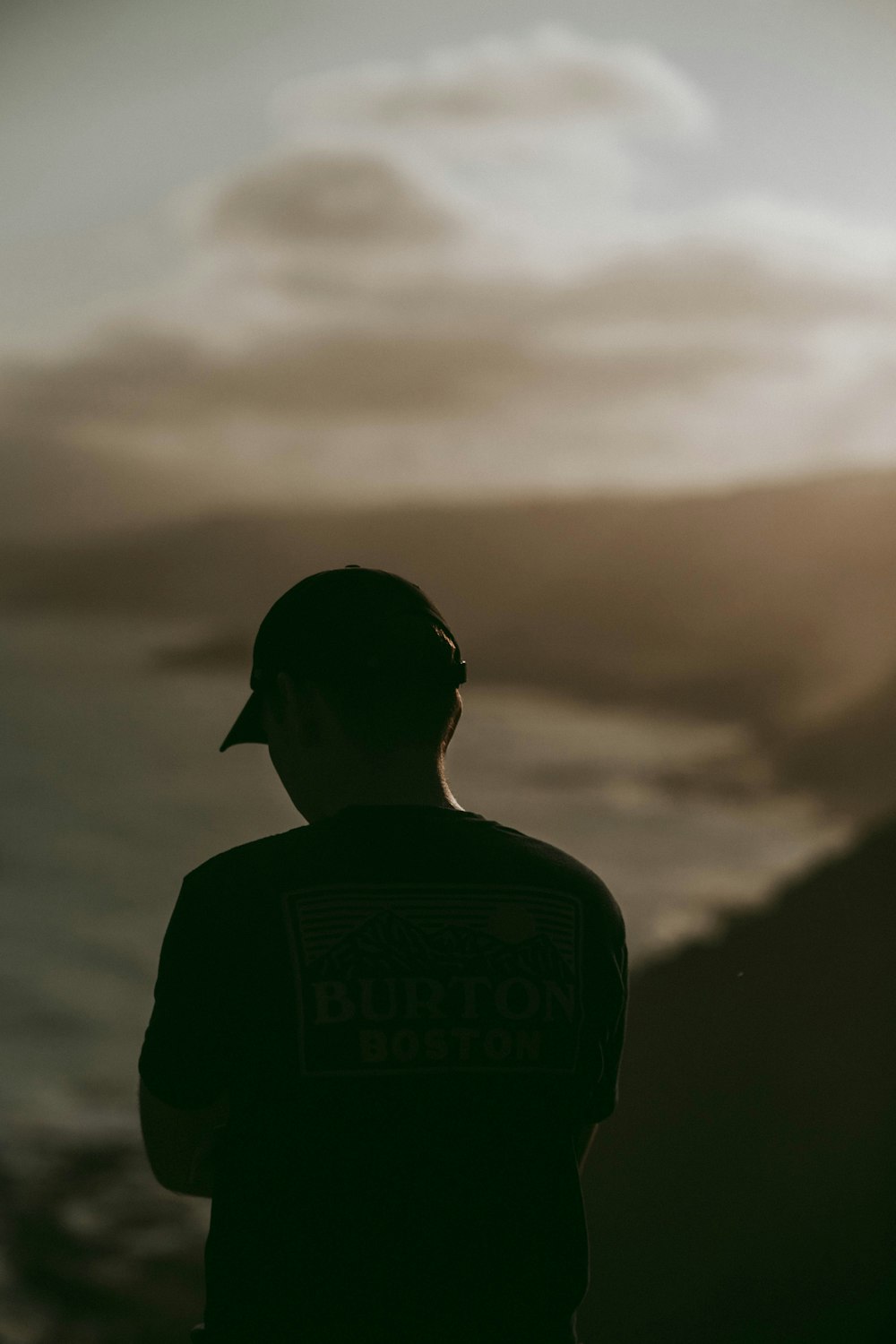 man in Burton shirt facing ocean