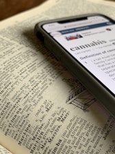 silver iPhone X displaying cannabis definition on top of dictionary