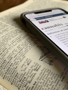 silver iPhone X displaying cannabis definition on top of dictionary