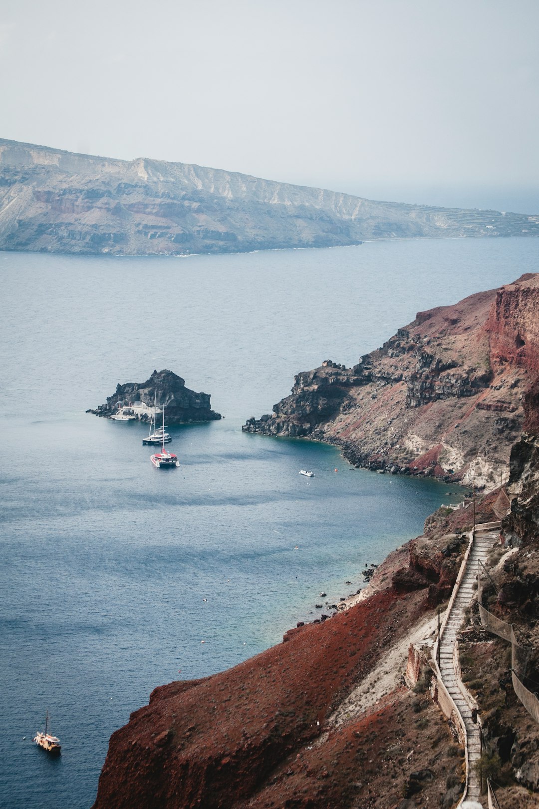 few boats on sea viewing cliff and mountain