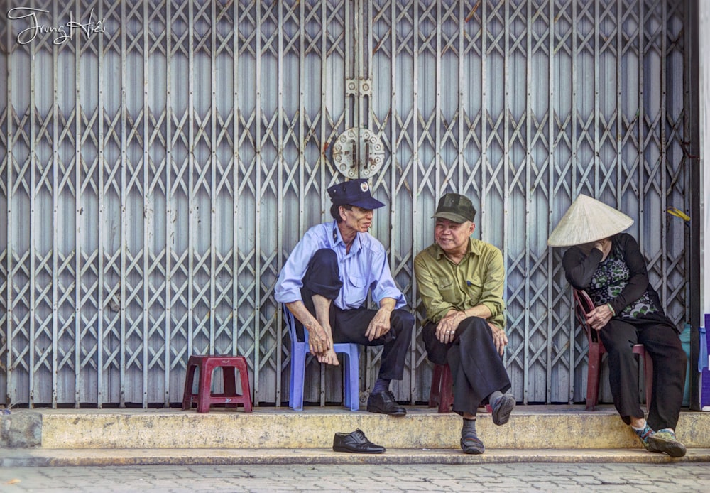 three person sitting on chairs beside gate