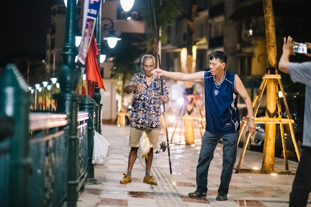 two men standing near another person taking photo of them