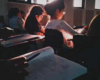 A student attentively working on a laptop in a bright classroom setting.
