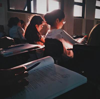 A student attentively working on a laptop in a bright classroom setting.