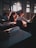 Students sit in a dimly lit classroom, focused on their work with sunlight streaming through the windows creating a warm glow. Papers and open books are visible, suggesting a study or lecture setting.