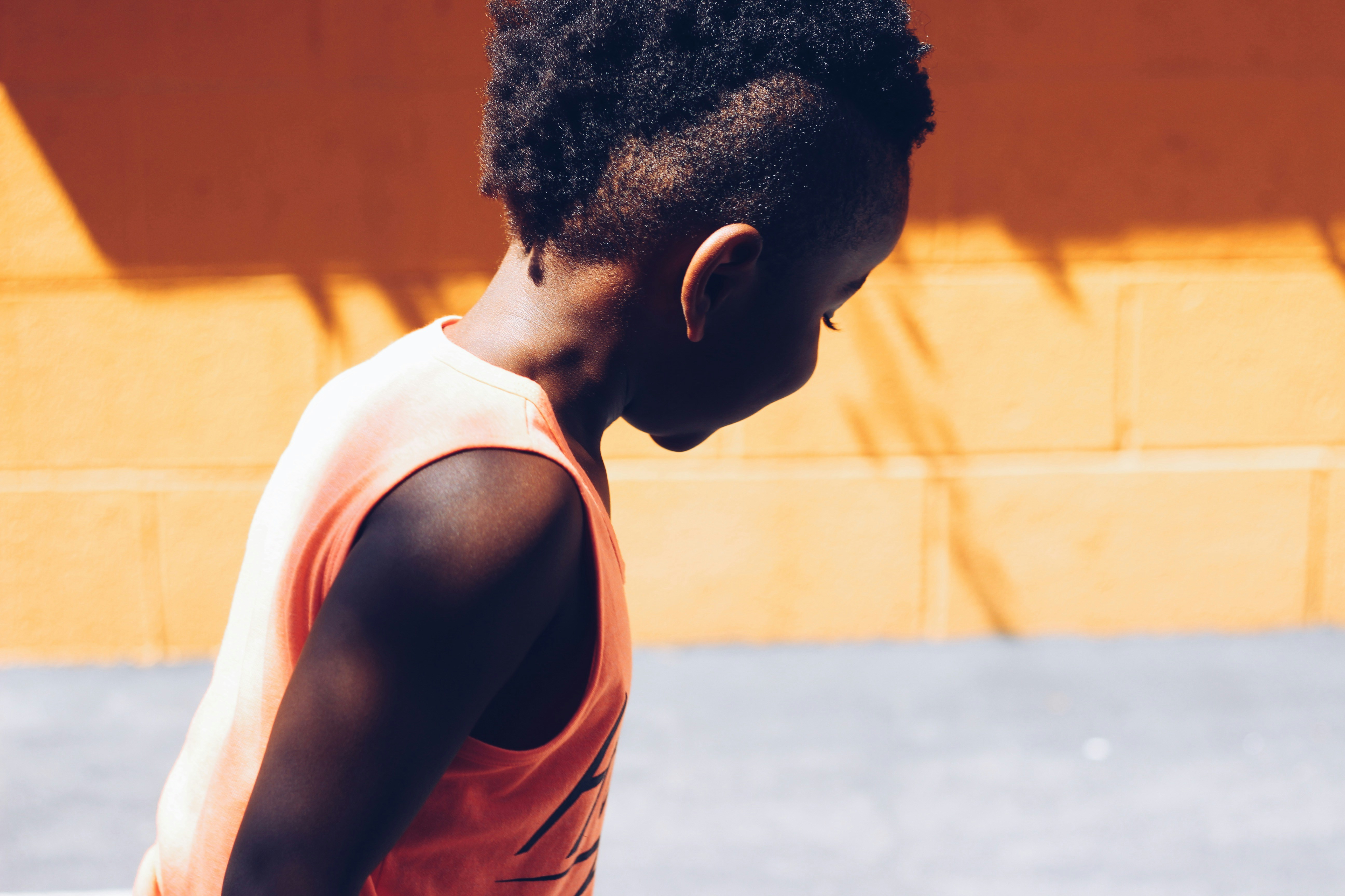 child wearing orange tank top looking right side