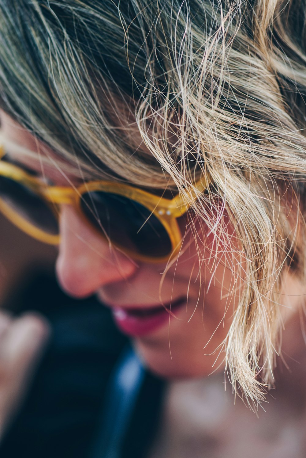 woman wearing yellow framed sunglasses looking down