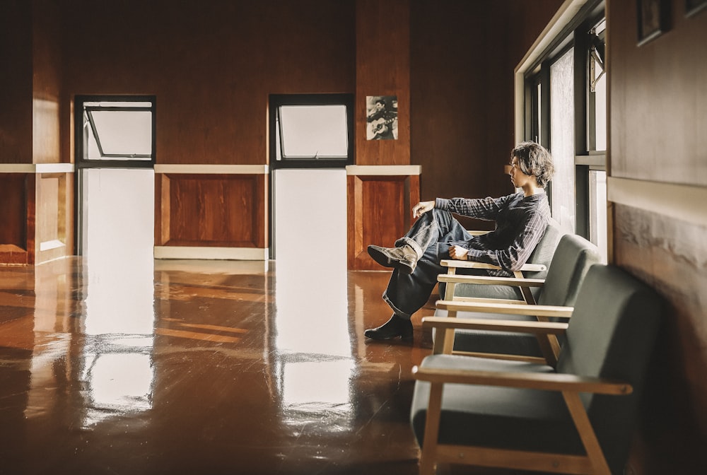 man sitting on armchair beside window