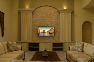 A cozy living room featuring a Samsung Frame TV displaying a tranquil landscape artwork.