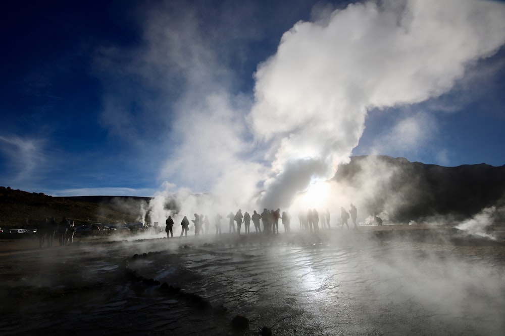 people surrounding a hot spring emitting smoke during golden hour