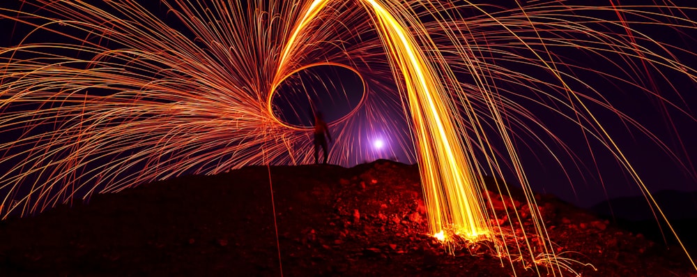 person on top of hill steel wool photography