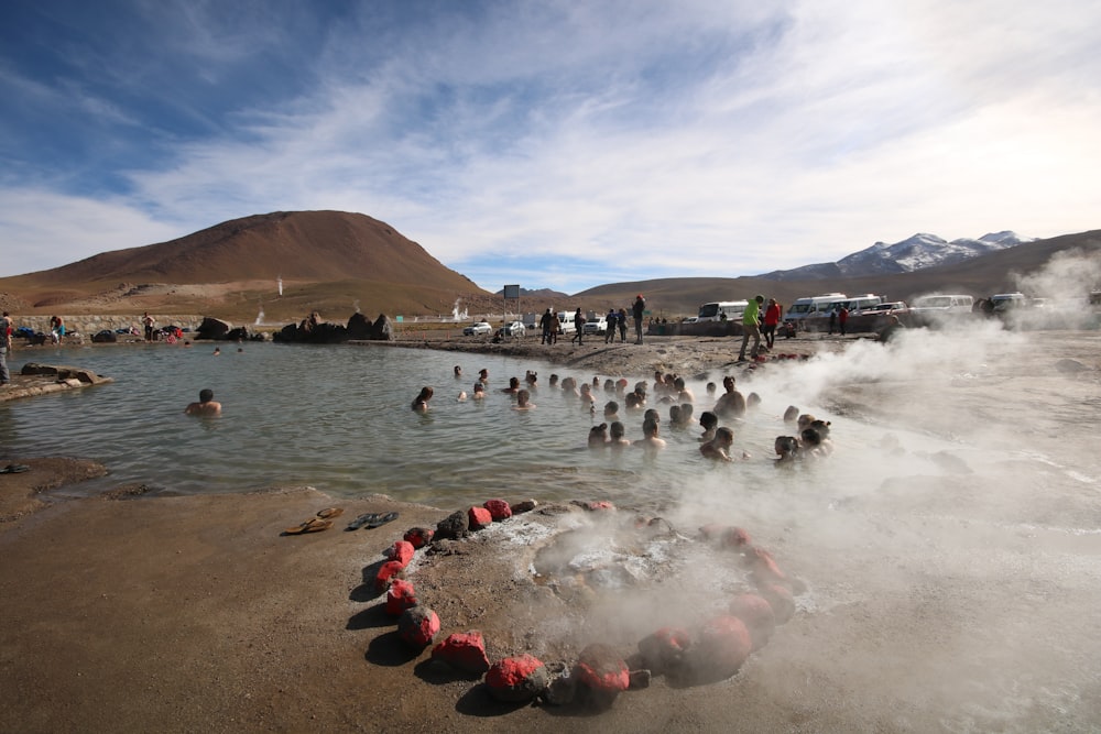people in hot spring by mountain during daytime