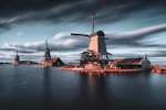 three windmills by the lake under grey cloudy sky