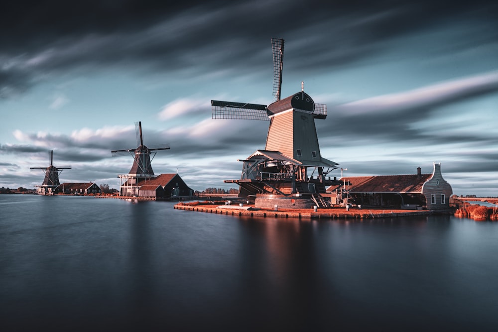 Drei Windmühlen am See unter grauem, bewölktem Himmel