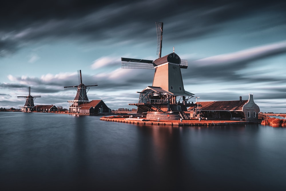 three windmills by the lake under grey cloudy sky