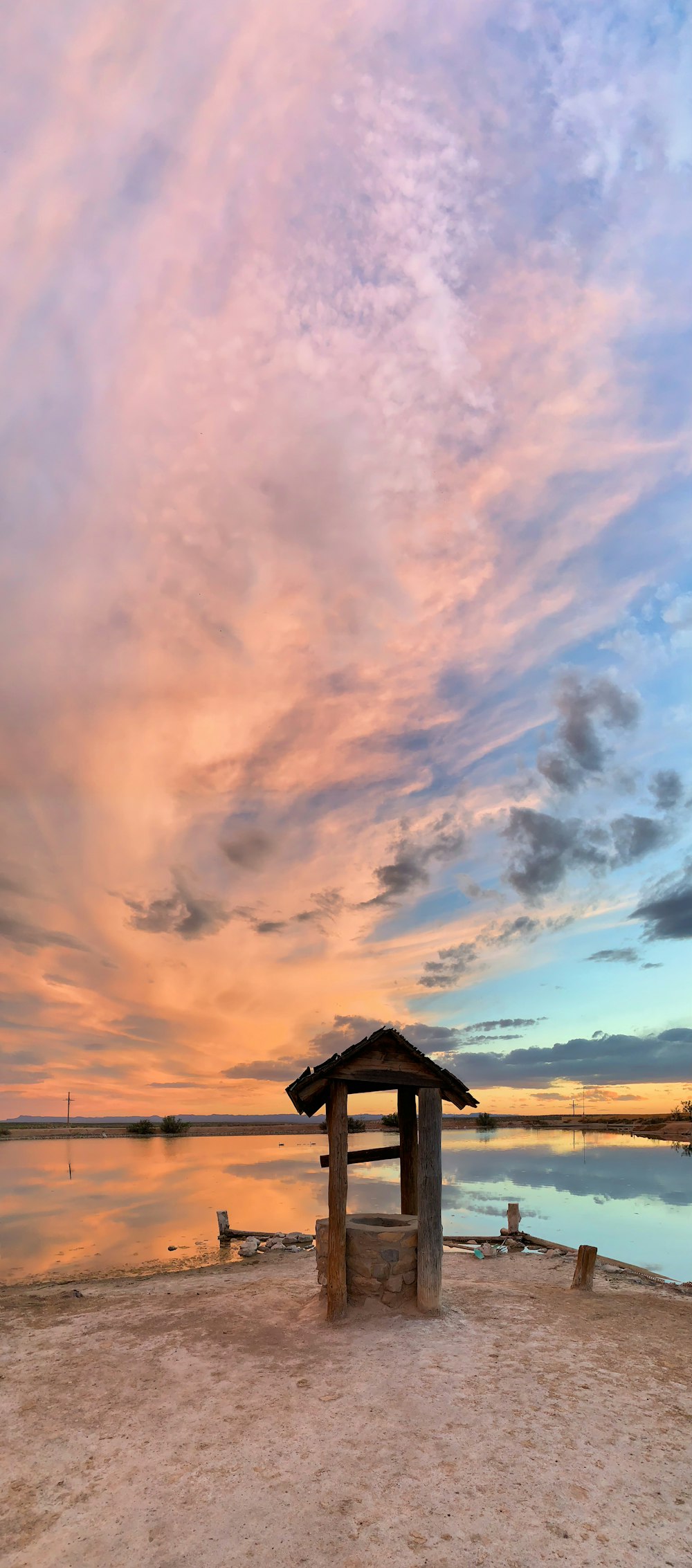 orange and grey cloudy sunset sky over water well and lake