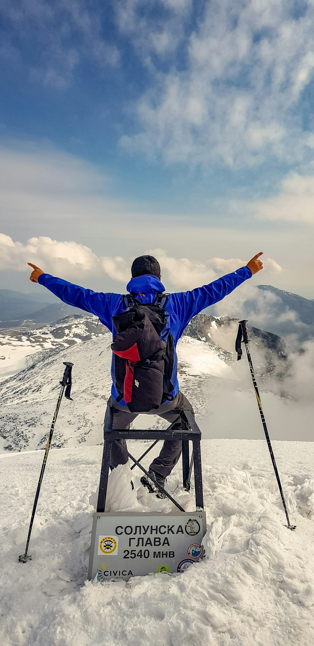 man spreading arms while sitting on chair on hill