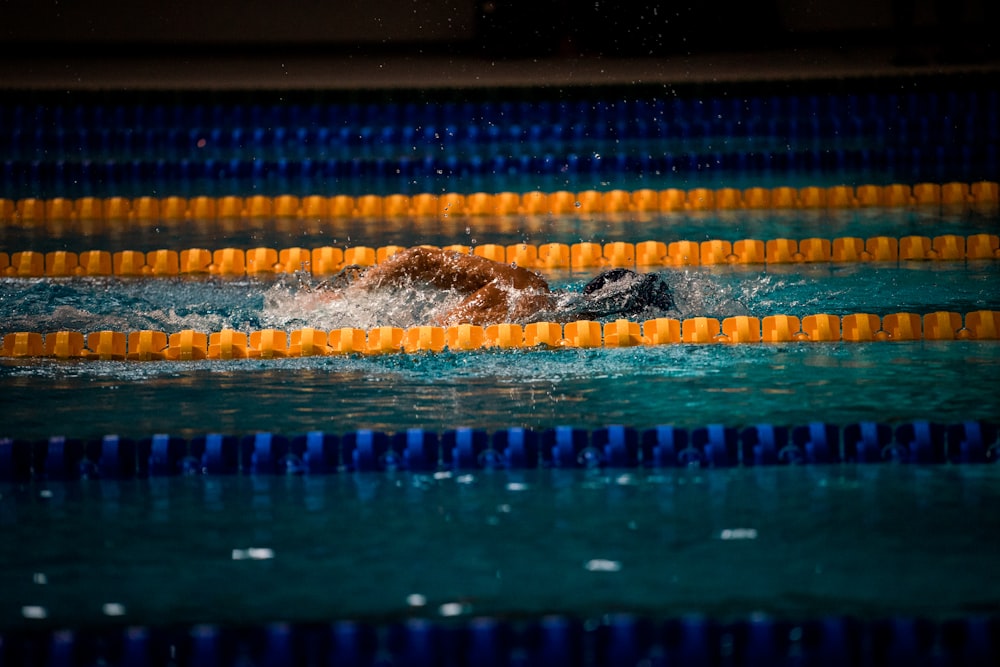 man swimming in pool with lane ropes