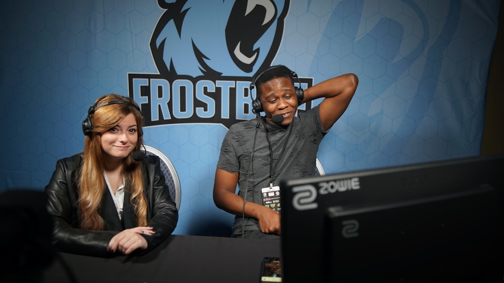 man and woman sitting on chair in front of monitor