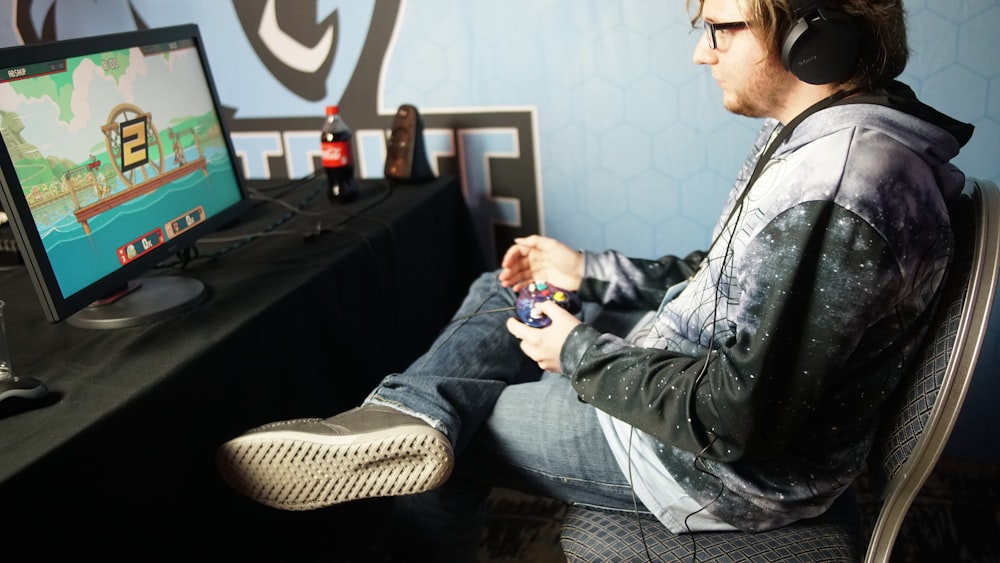 앉아서 컨트롤 패드를 사용하여 비디오 게임을 하는 남자