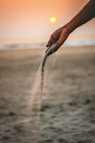 person picks up single handful of sand on the beach