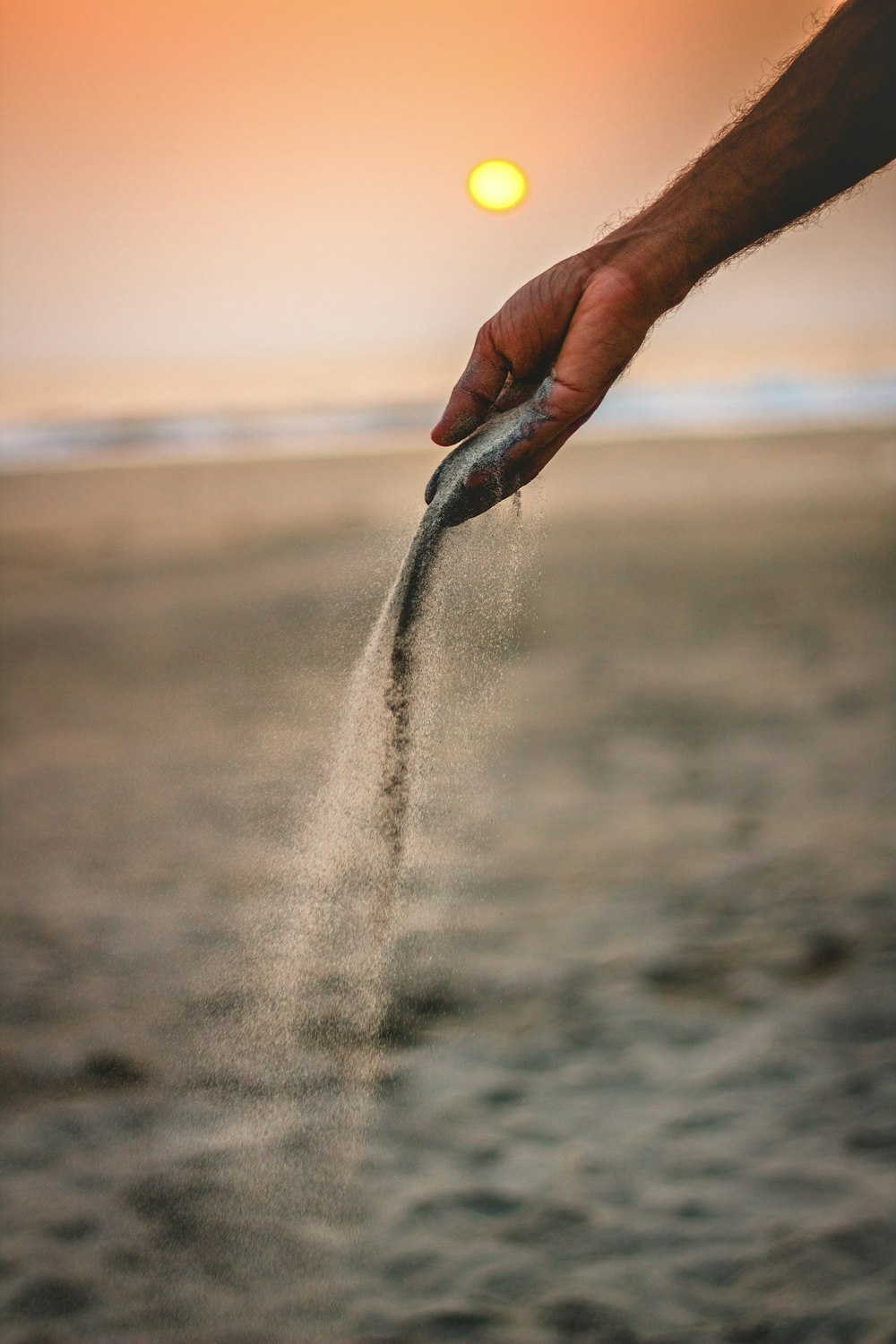 person picks up single handful of sand on the beach