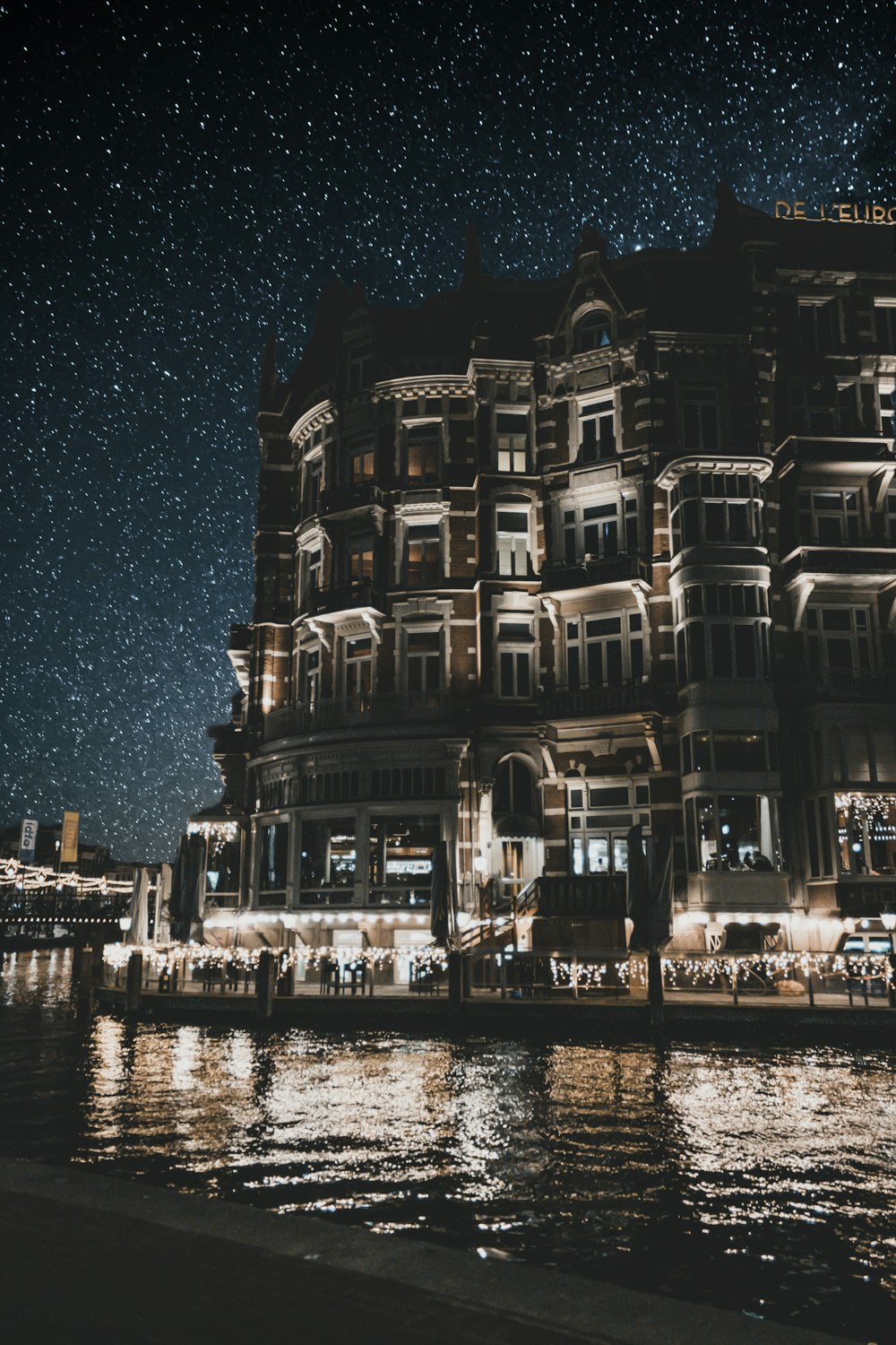 céu noturno estrelado sobre o edifício da loja ao longo do rio