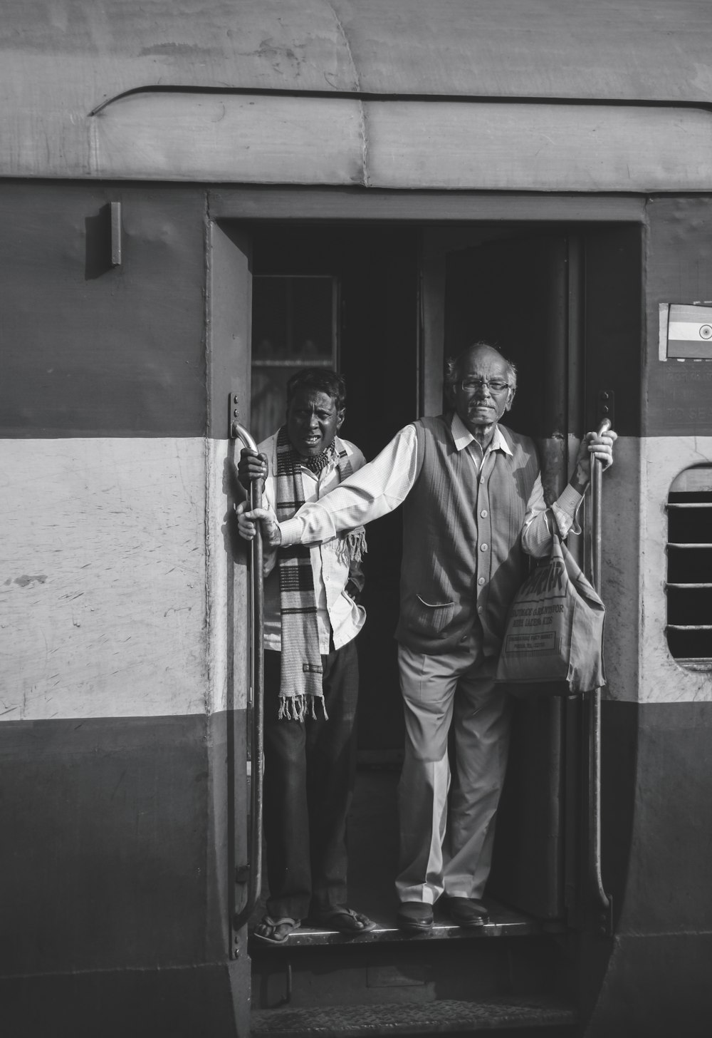 two men standing on the doorway of a train