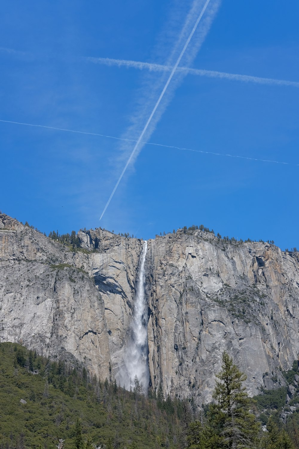 white contrails on a blue sky and waterfalls