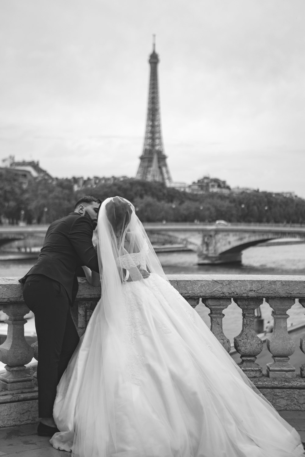 fotografia in scala di grigi della coppia di sposi di fronte alla Torre Eiffel
