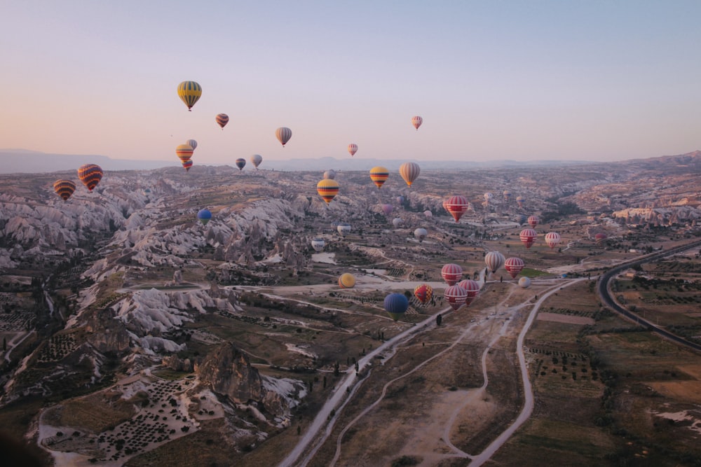 Heißluftballons am Himmel über Bergen und Straßen
