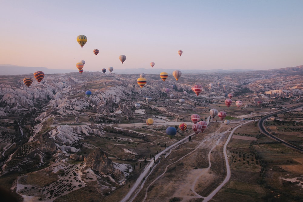 hot air balloons in the sky above mountains and roads