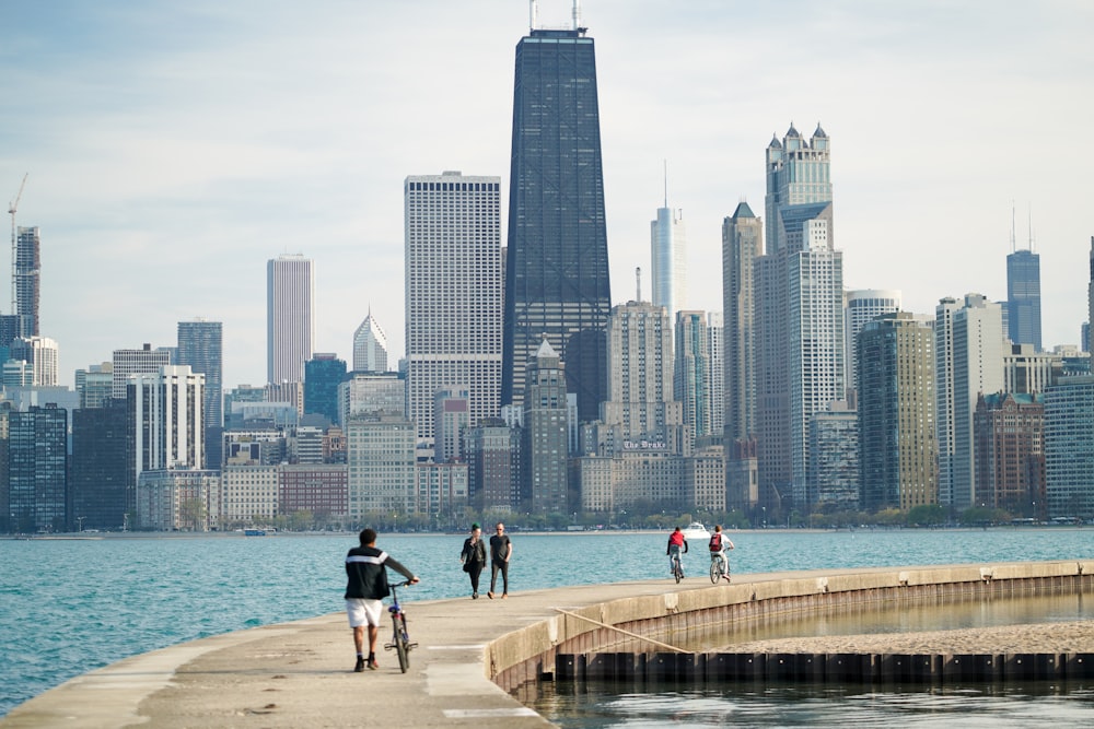 people walking and riding bikes on concrete dock near the city