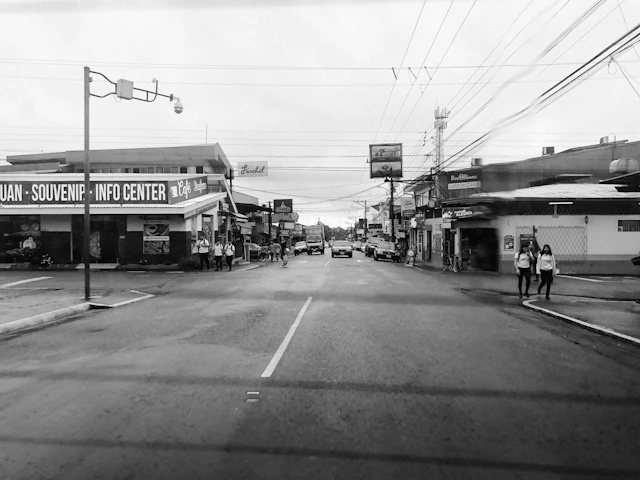 grayscale photo of road between buildings