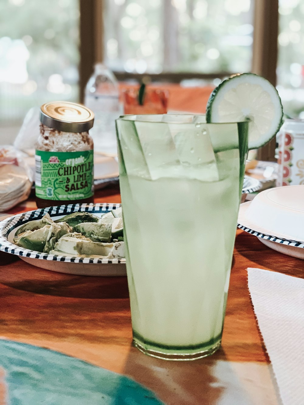 suco de limão com limão fatiado por cima perto de comida no prato ao lado de chipotle orgânico e pote de salsa de limão na mesa