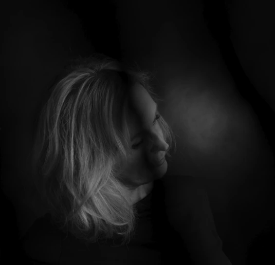 A serene black and white portrait with soft lilac lighting highlighting the subject's face.