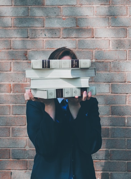 Image of a woman holding up a stack of books 