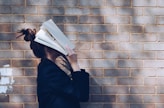 woman covering her face with white book